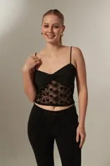Top de encaje negro con tirantes finos, diseño ajustado al cuerpo y detalle de nudo en el frente.