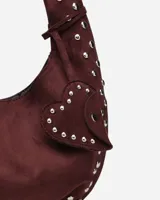 Bolso hobo color crema con tachas plateadas y cierre con botón magnético.
