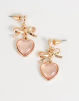Par de aros colgantes dorados con pasante en forma de corazón, moño y dije de corazón rosa.