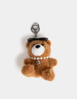 Llavero con dije de oso de peluche color marrón claro, con moño negro, collar de perlas y dije de corazón plateado.