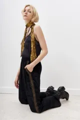 Pantalón palazzo negro de terciopelo con cintura elástica y detalle de bordado dorado en los laterales.