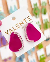 Par de caravanas fucsia con forma irregular y apliques de strass en el borde superior.