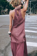 Vestido midi color lila, de cuello halter y sin mangas. La parte superior es de tejido arrugado y la falda es plisada. Tiene abertura en la espalda con cierre de botones ocultos.