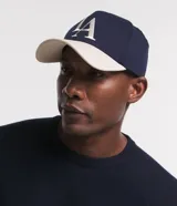 Gorra de sarga azul marino con visera curva color beige, bordado frontal con las letras LA en blanco y cierre ajustable en la parte posterior.