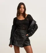 Short pollera negro de cuero sintético con diseño cruzado y costuras contrastantes.