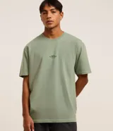 Remera verde salvia de corte relaxed, confeccionada en algodón más sostenible. Presenta cuello redondo, mangas cortas y estampa frontal con lettering y árboles.
