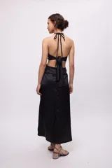 Vestido midi amarillo de satén con escote halter, trenzas en cuello y cintura, cut-outs laterales y falda recta.