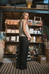 Pantalón de vestir negro de tiro alto, corte recto y pierna ancha. Presenta pliegues frontales y bolsillos laterales.