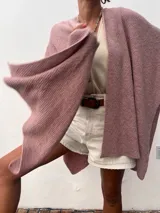 Ruana color rosa de tejido suave, con diseño sin mangas y caída amplia.