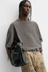 Camiseta color gris verdoso de punto tejido en hilatura de algodón, con cuello redondo, manga corta, efecto lavado y acabados irregulares.