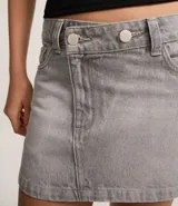 Minifalda de jeans azul oscuro, con cintura alta y cierre cruzado con botones. Presenta trabillas y bolsillos delanteros y traseros.