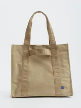 Bolso tote color beige con asas de tela con letras estampadas.