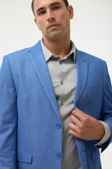 Ambo de traje azul marino, compuesto por saco de solapa en punta y pantalón a juego. Se combina con una camisa azul oscuro desabrochada.