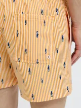 Short de baño naranja con rayas verticales blancas y estampado de tiburones azules. Cuenta con cintura elástica ajustable con cordón blanco.