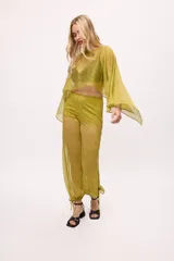 Pantalón negro traslúcido con corte ancho y ajuste en los tobillos.