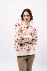 Sweater de lana color crudo con cuello alto y diseño de flores rojas y amarillas.