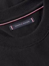 Buzo negro de cuello redondo marca Tommy Hilfiger, con logo estampado en el frente. Confeccionado en felpa de puro algodón, con cuello, puños y bajo de punto canalé. Logo de Tommy Hilfiger bordado en la manga.