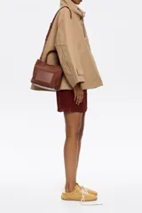 Bolso tote pequeño marca Bimba y Lola, modelo Chihuahua, color marrón. Confeccionado en nylon con estructura blanda, doble asa de mano y asa de tejido, piezas de piel, cierre con botón de presión, logo grabado, acabados metálicos, bolsillo interior e interior con placa metálica logotipada.