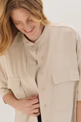 Sobrecamisa celeste de corte recto, con cuello mao, mangas 3/4 con puños y cierre frontal con botones. Tiene dos bolsillos de parche en el pecho.