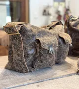Bolso marrón de cuero con efecto gastado, con múltiples bolsillos frontales con cierre metálico.