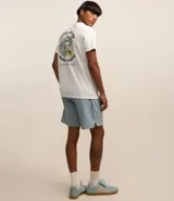 Remera blanca de algodón con cuello redondo y manga corta. Estampa en la espalda con diseño de esqueleto surfeando una ola junto a una palmera.