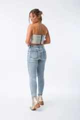 Pantalón de jean celeste con roturas en las rodillas, corte skinny, tiro alto y cierre frontal con botones.