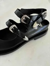 Ballerinas de cuero color marrón topo, con punta fina y dos tiras con hebillas plateadas.