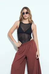 Pantalón blanco de tiro bajo, estilo baggy o aladín, con silueta amplia y fluida, cintura elastizada y puños ajustados en los tobillos.