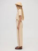 Pantalón de algodón negro, corte holgado y pierna ancha con pretina elástica. Presenta rayas bicolor al costado en blanco y celeste. Calce de tiro alto.