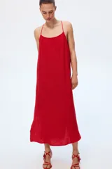 Vestido tobillero rojo de muselina de algodón suave, corte holgado con breteles finos ajustables, escote recto, espalda escotada y bajo recto con abertura pronunciada en los laterales.