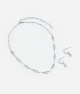 Conjunto de collar y caravanas plateados con colgantes de estrella y strass. El collar es de cadena con eslabones y estrellas colgantes. Las caravanas son aros pequeños con una estrella colgante.