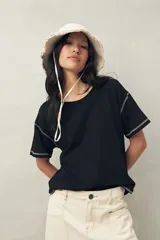 Remera negra de manga corta y cuello redondo, confeccionada en algodón liviano. Presenta costuras a contratono visibles en mangas y ruedo.