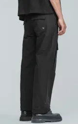 Pantalón cargo negro de corte recto con bolsillos laterales con solapa y etiqueta con texto en la pierna derecha.