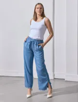 Pantalón celeste de lyocell, corte ancho, con cintura elastizada ajustable con cordón y ruedo desflecado con tajos laterales.