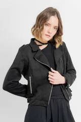 Chaqueta negra tipo biker de gamuza sintética con cuello solapa y manga larga con trabillas en los hombros. Tiene bolsillos delanteros con cremallera metálica y cierre frontal con cremallera.