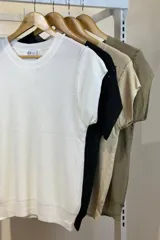 Blusa color beige de hilo con cuello redondo y mangas cortas con detalle de cadena plateada en los hombros.