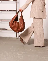 Bolso marrón oscuro de cuero sintético con forma ovalada y asa corta.