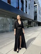 Vestido negro largo con escote en V, mangas cortas tipo kimono, falda cruzada con abertura y cinturón fino con strass.