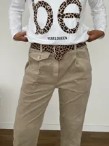 Pantalón color beige de corte ligeramente suelto, confeccionado en algodón y elastano. Incluye un cinto de animal print.
