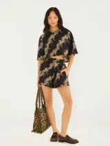 Short negro con estampado de cebras y hojas color ocre, de tela liviana y cintura elástica.