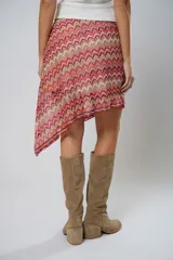 Minifalda roja con estampado de ondas en tonos rosados y beige, con corte irregular y cinturón marrón.