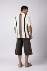 Remera de hombre tejida en algodón color crudo, con textura piqué y rayas verticales marrones y negras.