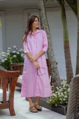 Vestido largo rosa con botones frontales y mangas tres cuartos, en un diseño sencillo y elegante.