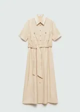Vestido midi color beige, estilo camisero, de manga corta y tejido fluido. Tiene cuello camisero, cierre frontal con botones, lazo ajustable en la cintura y dos bolsillos de parche en el pecho.
