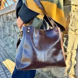 Bolso tipo tote de cuero color marrón, con doble asa de hombro y cierre superior.