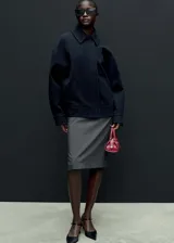 Falda midi gris con raya diplomática, diseño lápiz, cinturón desmontable y abertura en el bajo.