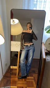 Conjunto de top y pantalón de encaje negro. El top es de escote bardot y mangas largas acampanadas. El pantalón es de corte palazzo.