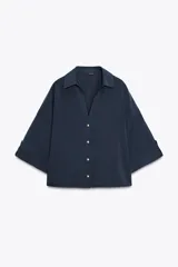 Camisa azul marino de cuello solapa con escote pico y manga ancha por debajo del codo con trabilla y botón. Cierre frontal con botones.
