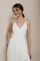 Vestido largo blanco con escote en V, breteles finos y falda plisada con abertura lateral. El corpiño está adornado con cuentas de cristal.