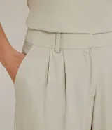 Pantalón zanahoria color beige de liocel, con pliegues delanteros, bolsillos laterales y cierre con cremallera y botón.